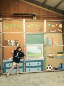 A child posing in front of a backdrop of "Booker's Room".